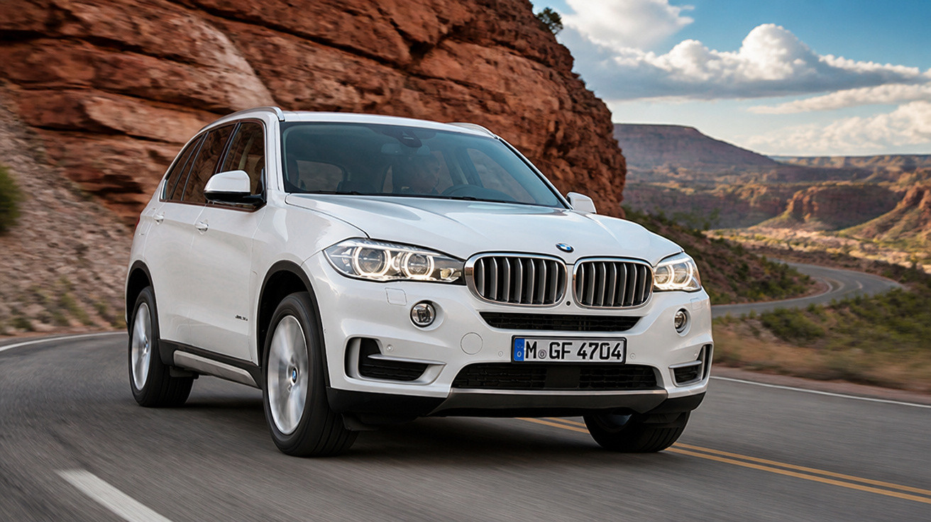Weisser BMW SUV auf kurviger Strasse mit felsiger Wüstenlandschaft im Hintergrund bei Tageslicht.